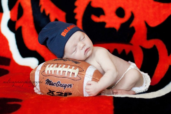 "baby holding football image"